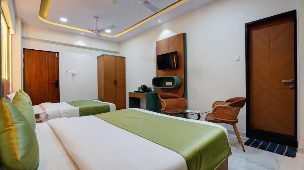 a hotel room with a bed and a tv and chairs at Hotel Balaji Residency Dombivali in Dombivli