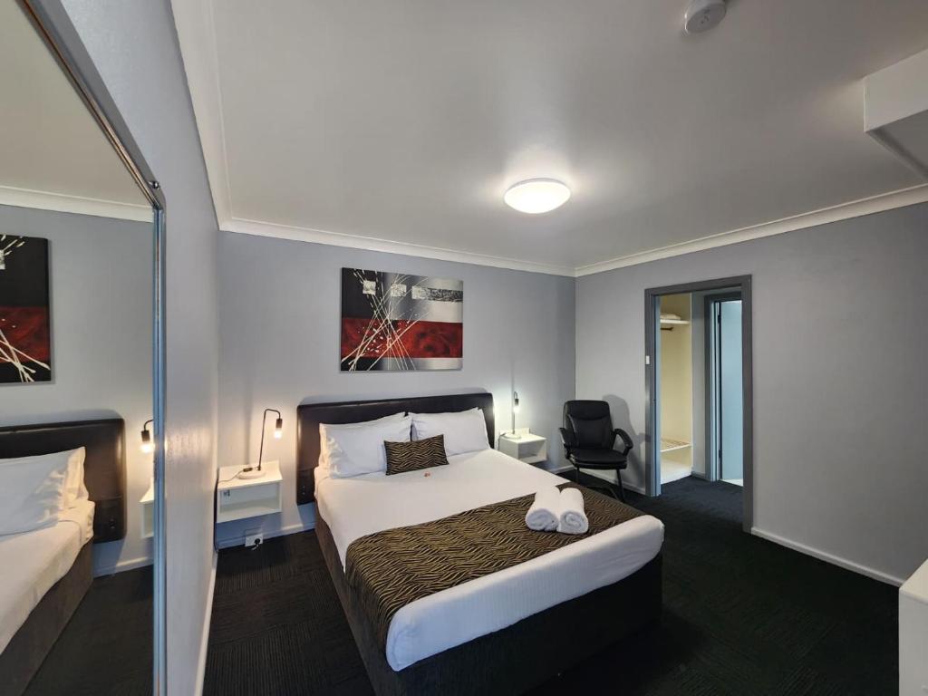 a hotel room with a bed and a chair at Crest Motor Inn in Queanbeyan