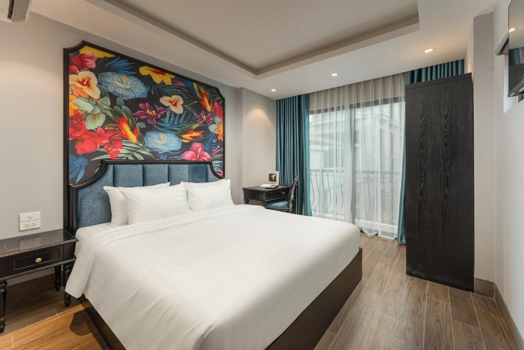 a bedroom with a large bed and a painting on the wall at Aurora Hotel & Apartment in Hanoi