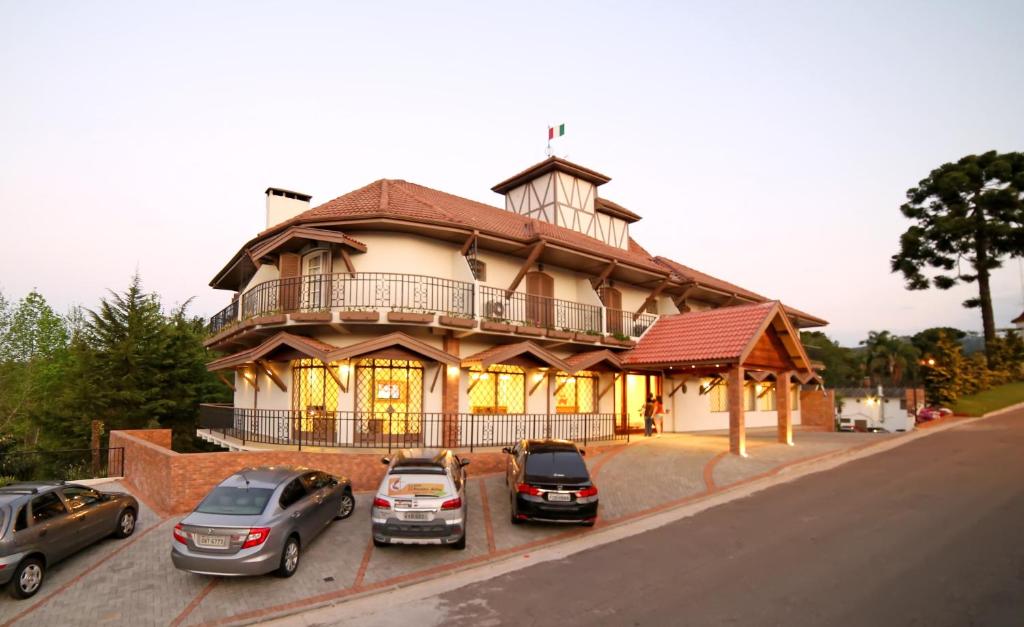 une grande maison avec des voitures garées devant elle dans l'établissement Moinho Itália Hotel, à Campos do Jordão