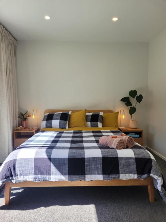 a bedroom with a black and white bed with yellow pillows at Clearwater Private Guest Suite in Dunedin