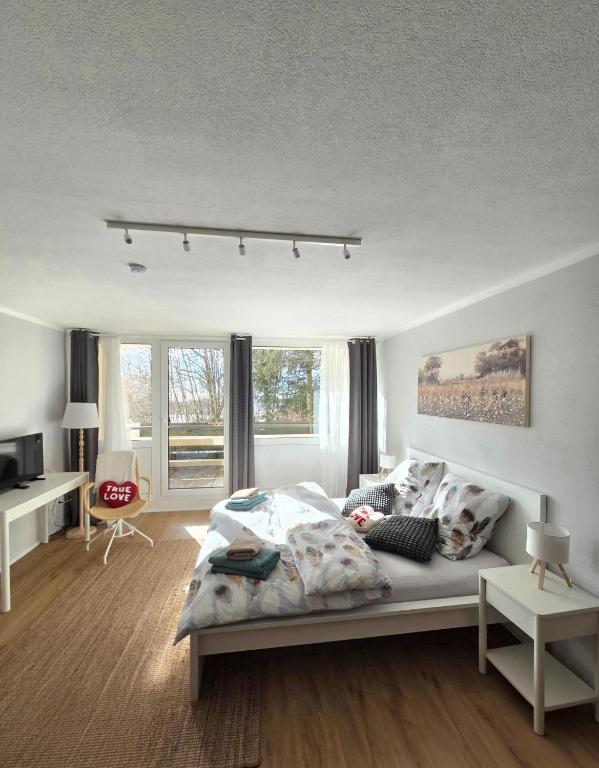 a white bedroom with a bed and some windows at Waldfeder Apartment mit Pool und Fitnessraum, neu und vollsaniert in Sankt Englmar