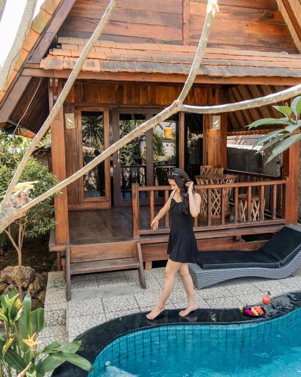 a woman walking by a pool in front of a house at Yoki's Bungalows in Kuta Lombok