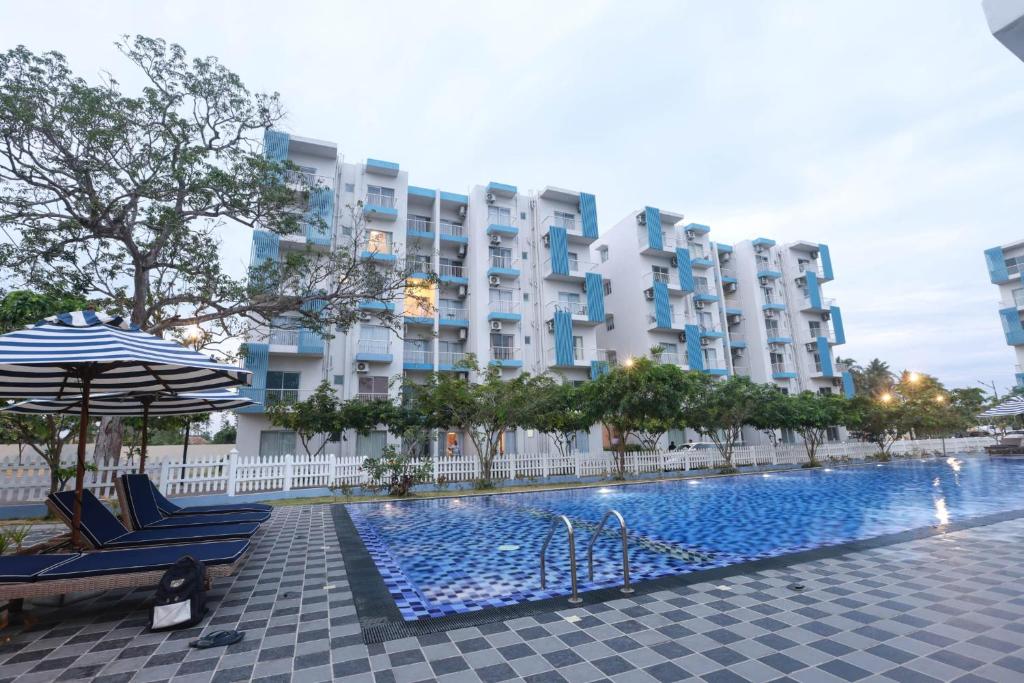 a hotel with a swimming pool and two chairs and an umbrella at Santorini Negombo in Negombo