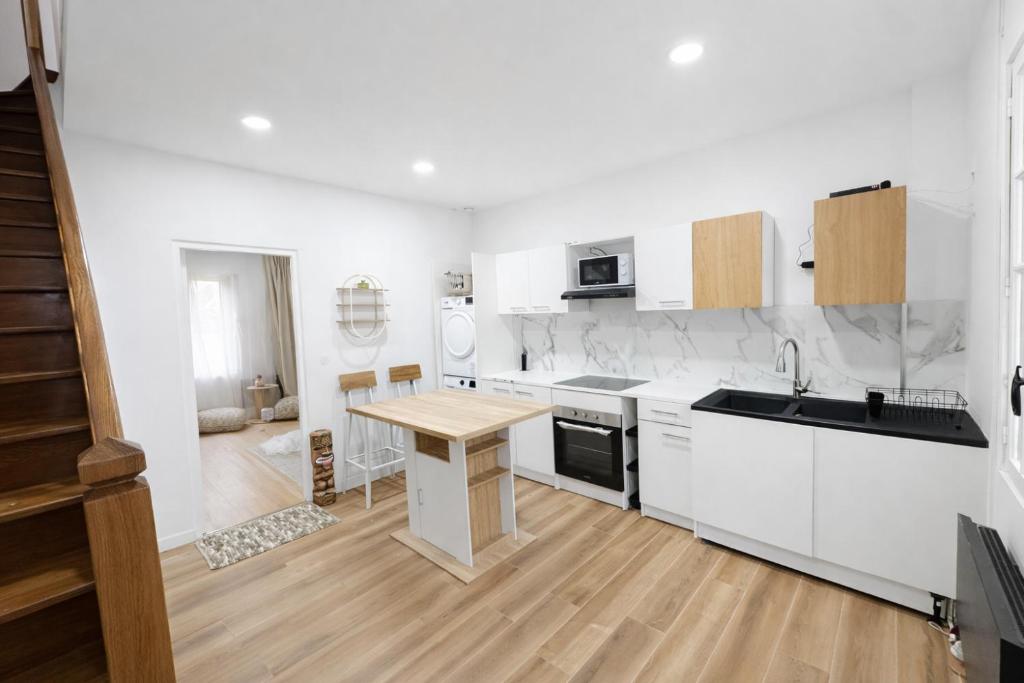 a kitchen with white cabinets and a wooden table at Maison Connectée Serenia in Méru