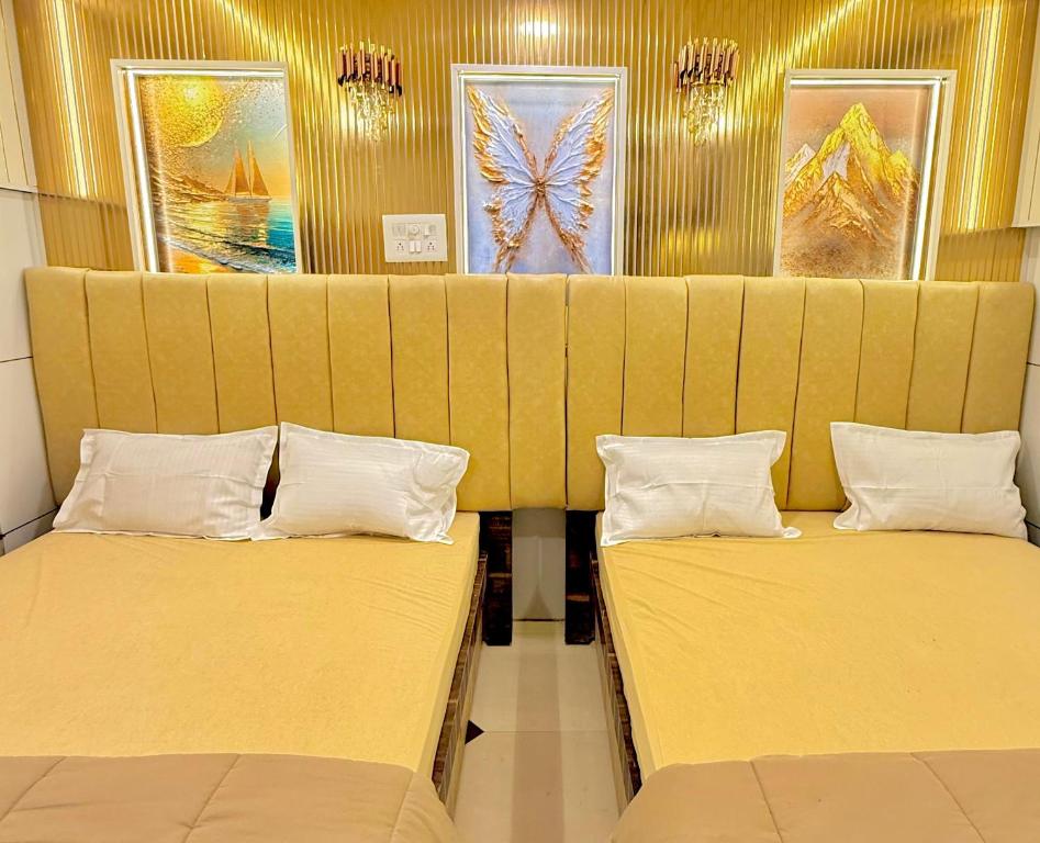 two beds in a room with yellow walls at Hotel rajmahel chotila in Chotila