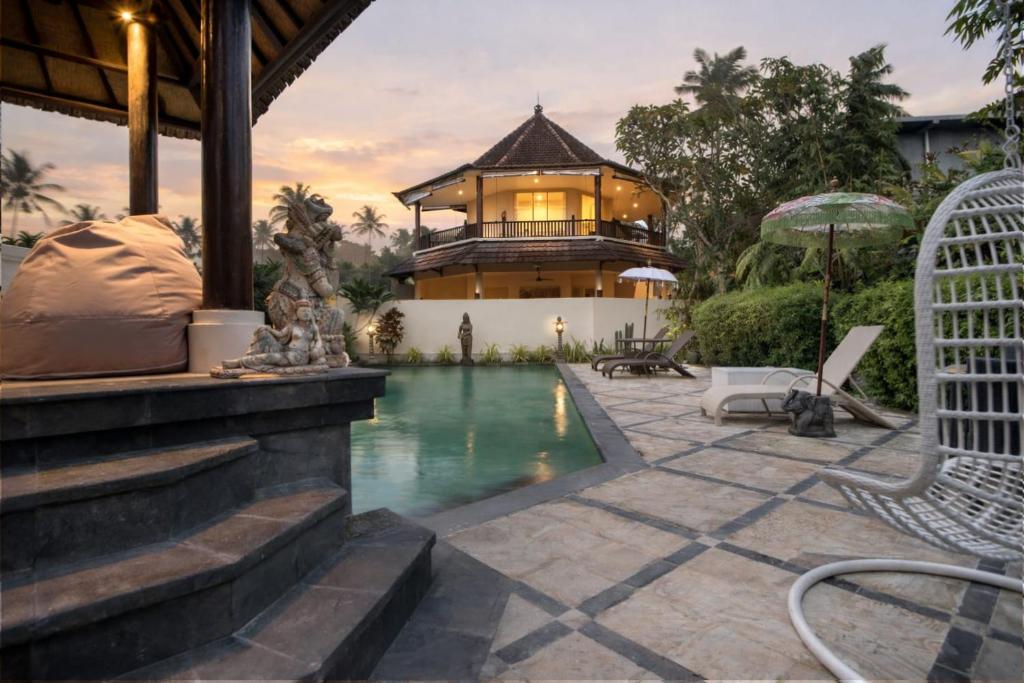 a house with a swimming pool in front of a house at Gajah Biru Bungalows in Ubud