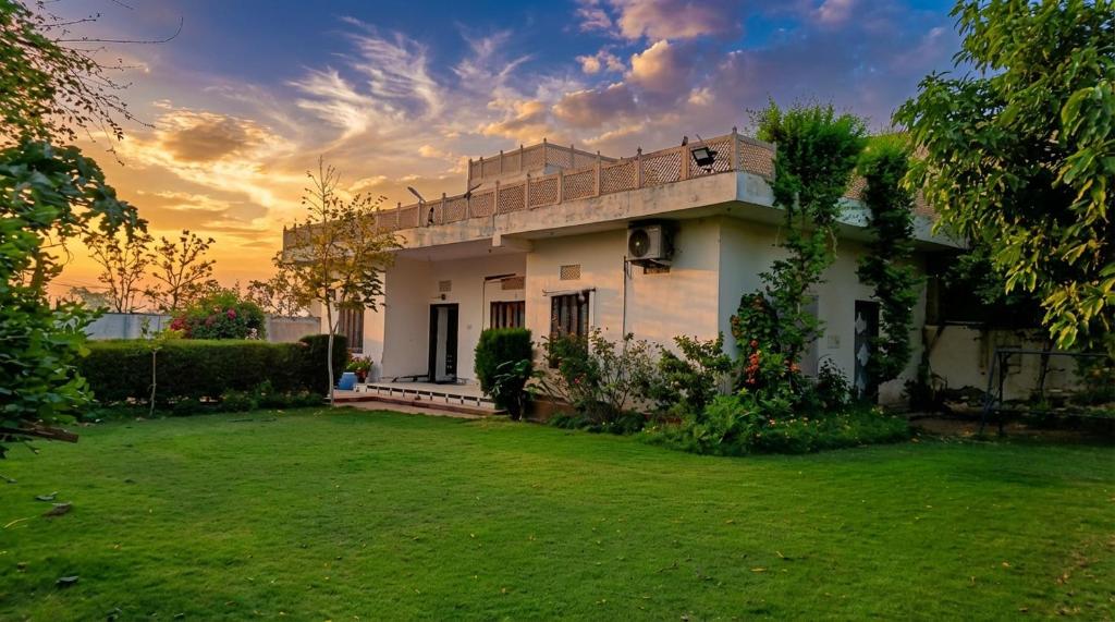 a house in a yard with a sunset in the background at Shree Govindam kunj Villa in Jaipur