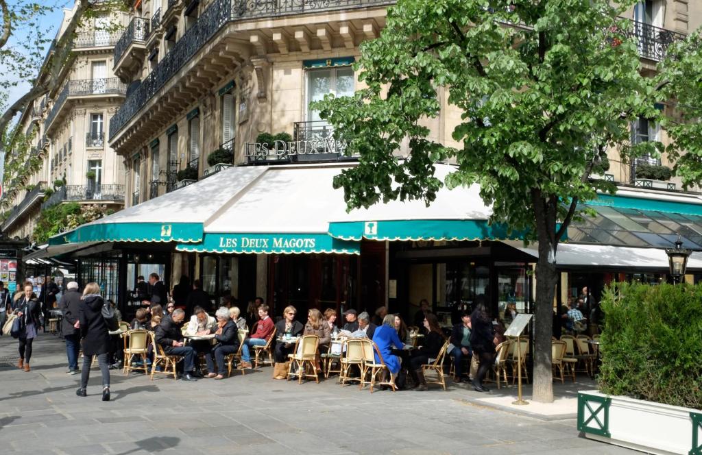 um grupo de pessoas sentadas em mesas fora de um restaurante em Apartment Bac St. Germain em Paris