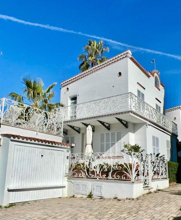 a white house with a white fence and palm trees at Villa Solaris in Sanremo