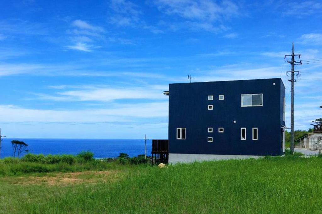 a building on the side of a field with the ocean at Saraswati in Nakijin
