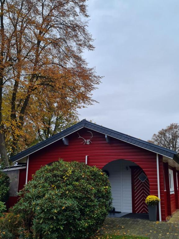 a red house with a white garage at Holzhaus im Schwedenstil in Scharnhorst