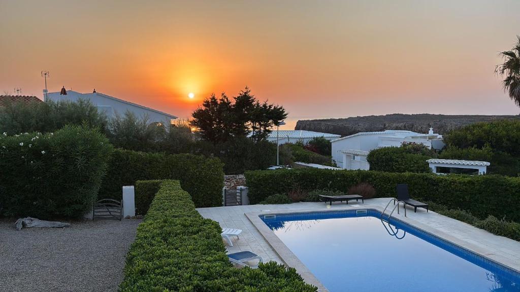 a swimming pool with a sunset in the background at Duplex Laura in Es Mercadal