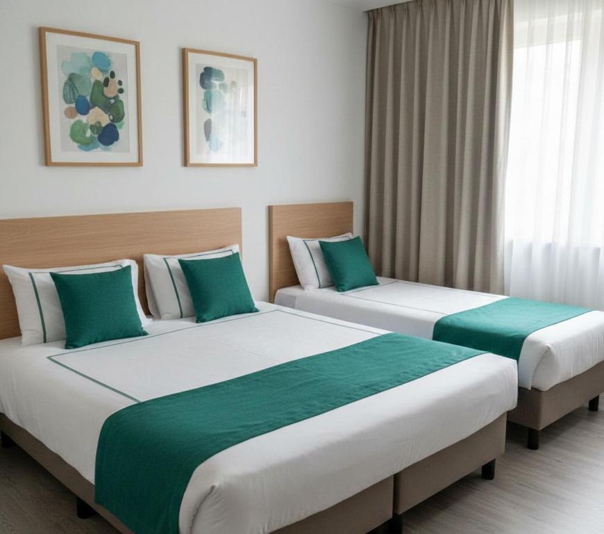 two beds in a hotel room with green and white at hayal hotel in Tokat