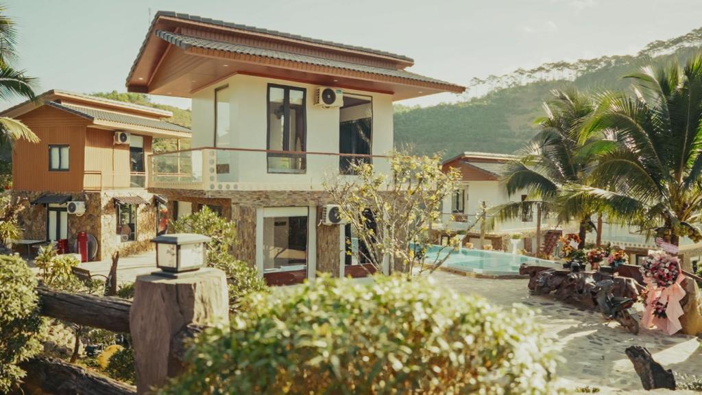 a villa with a swimming pool and a house at Homestay Minano in Mock Den