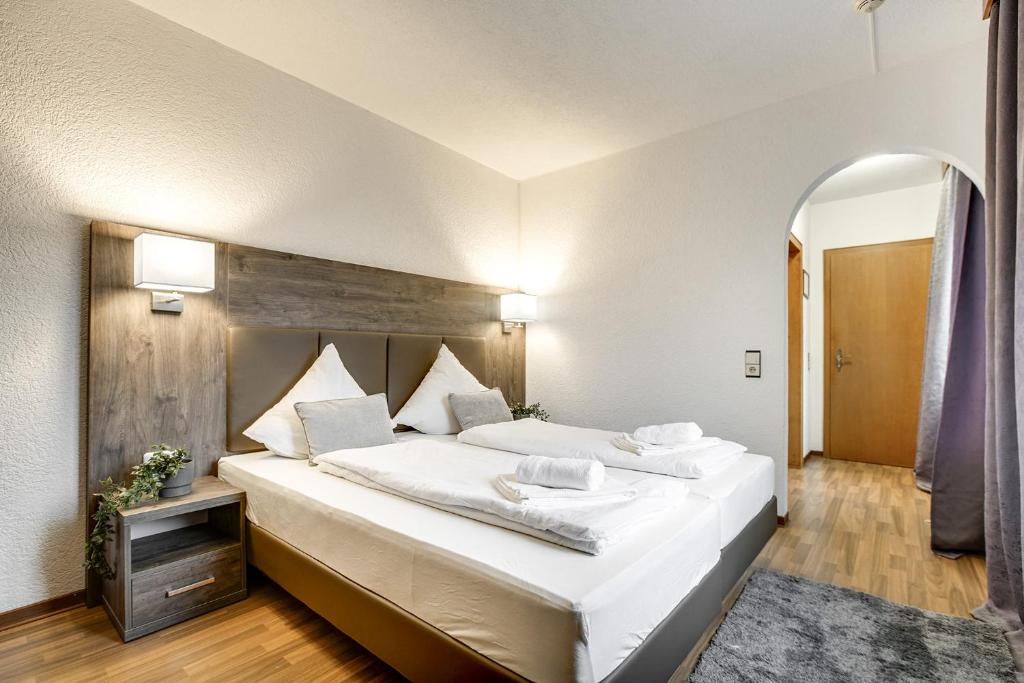 a bedroom with a large bed with white sheets at Hotel Relais Königsberg in Aachen