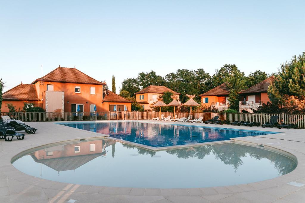 a swimming pool with chairs and a house in the background at Chez domi piscine résidence claire rive in Prayssac