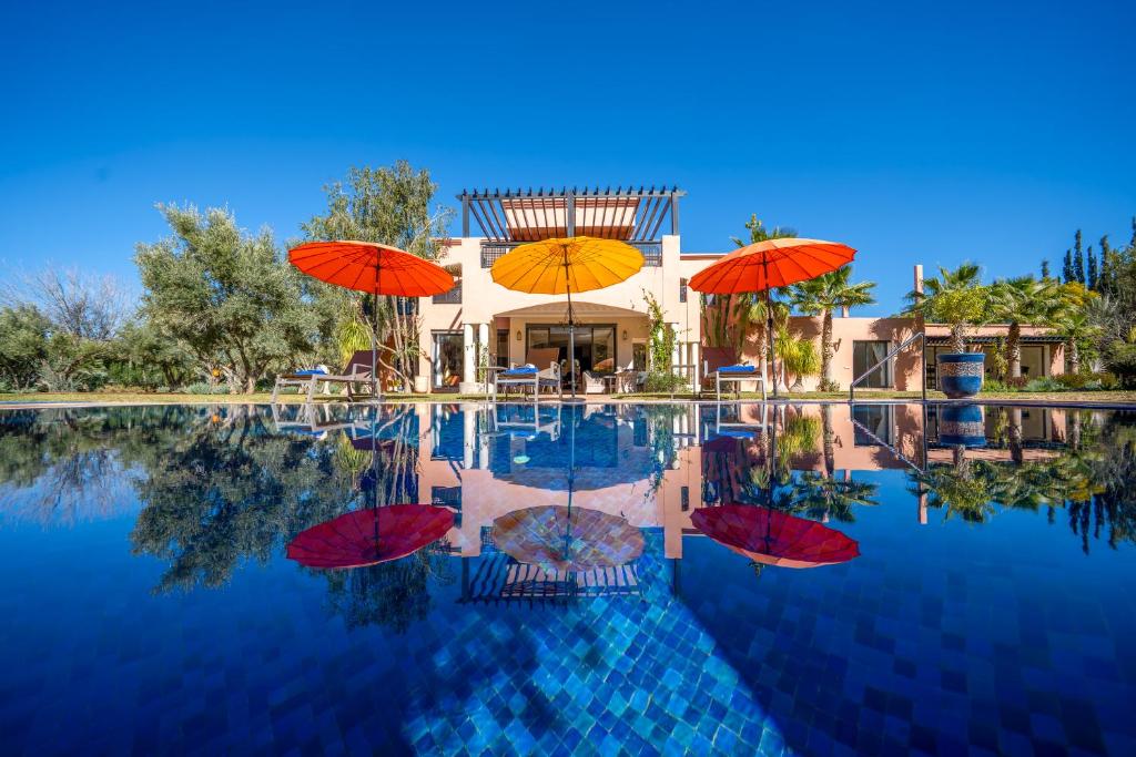 a swimming pool with umbrellas on top of it at Villa JUZYAN une parenthèse de bien-être et de convivialité in Marrakesh