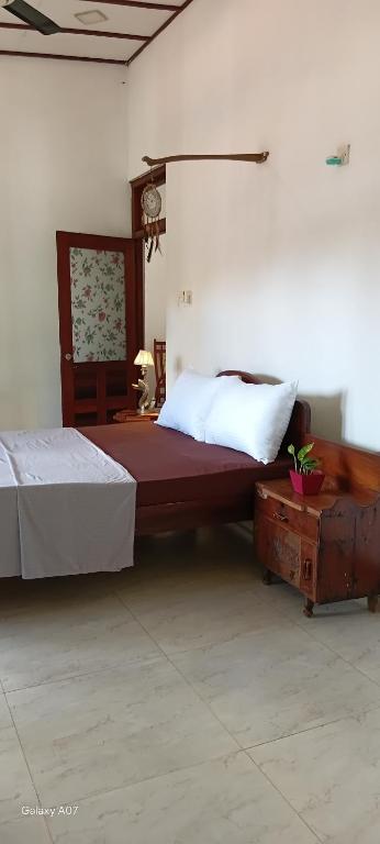 a bedroom with a large bed and a table at Wooden hostel in Weligama
