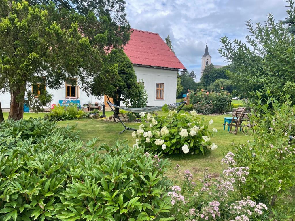 a white house with a red roof and some flowers at Na chalupu do Líšnice in Líšnice