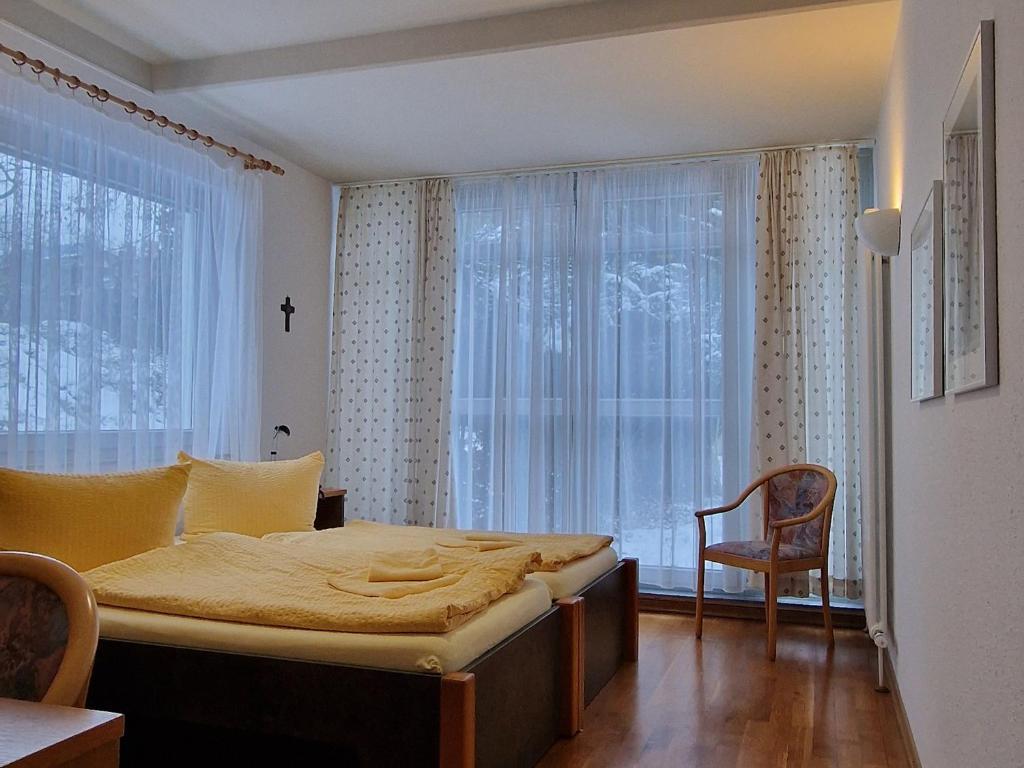 a bedroom with a bed and a chair and a window at Gästehaus Dominikus in Leipzig