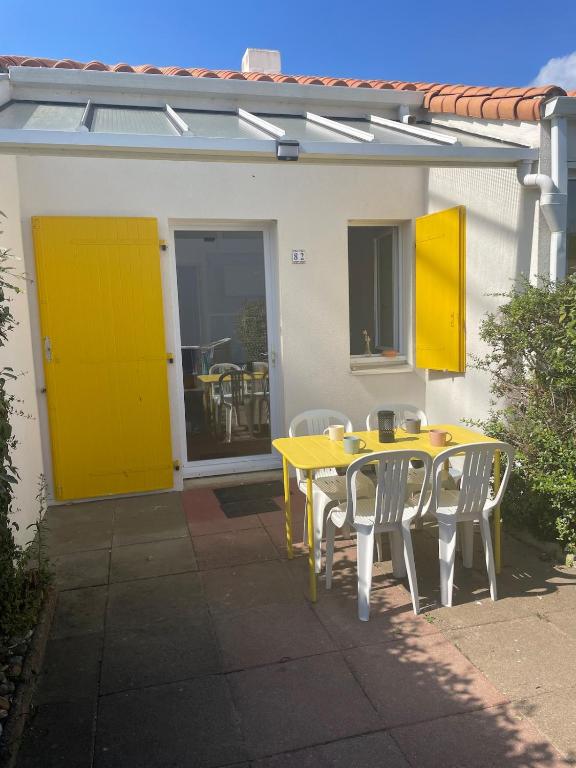 a yellow table and chairs in front of a house at Maisonnette de Plage in Saint-Hilaire-de-Riez