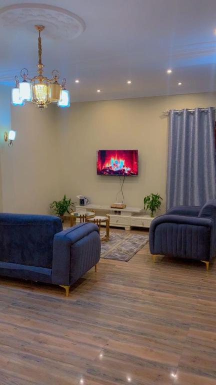 un soggiorno con due divani blu e una TV di MRGAppart a Brazzaville