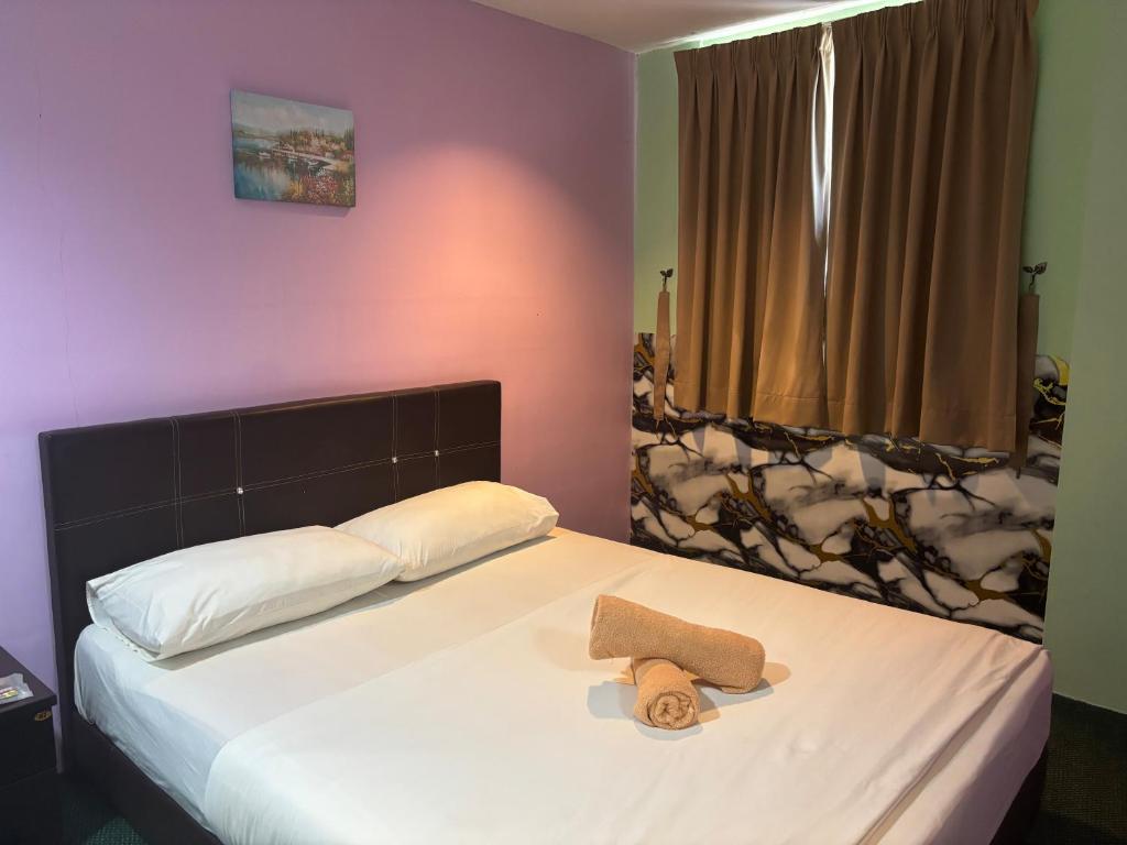 a bedroom with a bed with two towels on it at Hotel O Peneka Inn in Kota Bharu