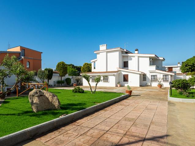 a large white building with a rock in the grass at Domo de Iannas-House Live Express in Quartu Sant'Elena