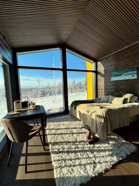 a bedroom with a bed and a desk and a large window at Mystical Lapland Suite in Rovaniemi