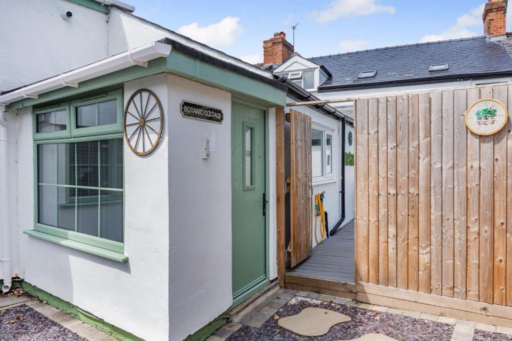 a cottage with a green door and a wooden fence at Botanic Cottages in Southport