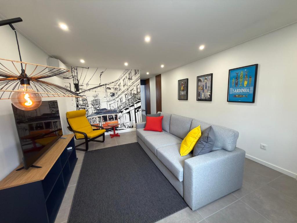 a living room with a gray couch and yellow pillows at Alma do Tejo - Alma Nossa in Montijo