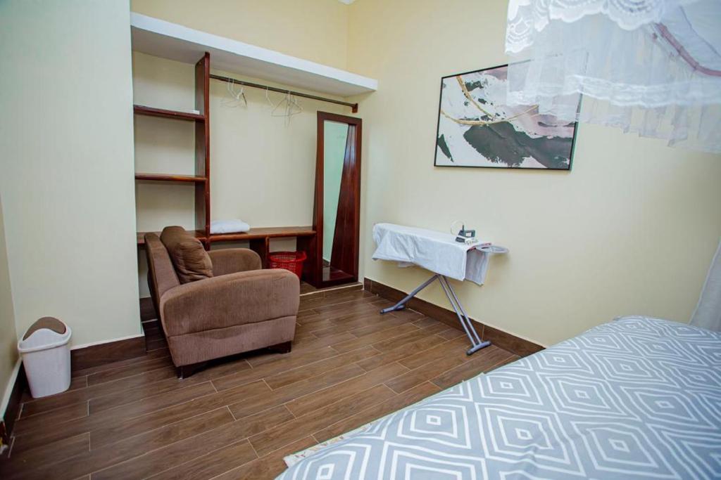 a bedroom with a bed and a chair and a table at Nadyapartment in Dodoma