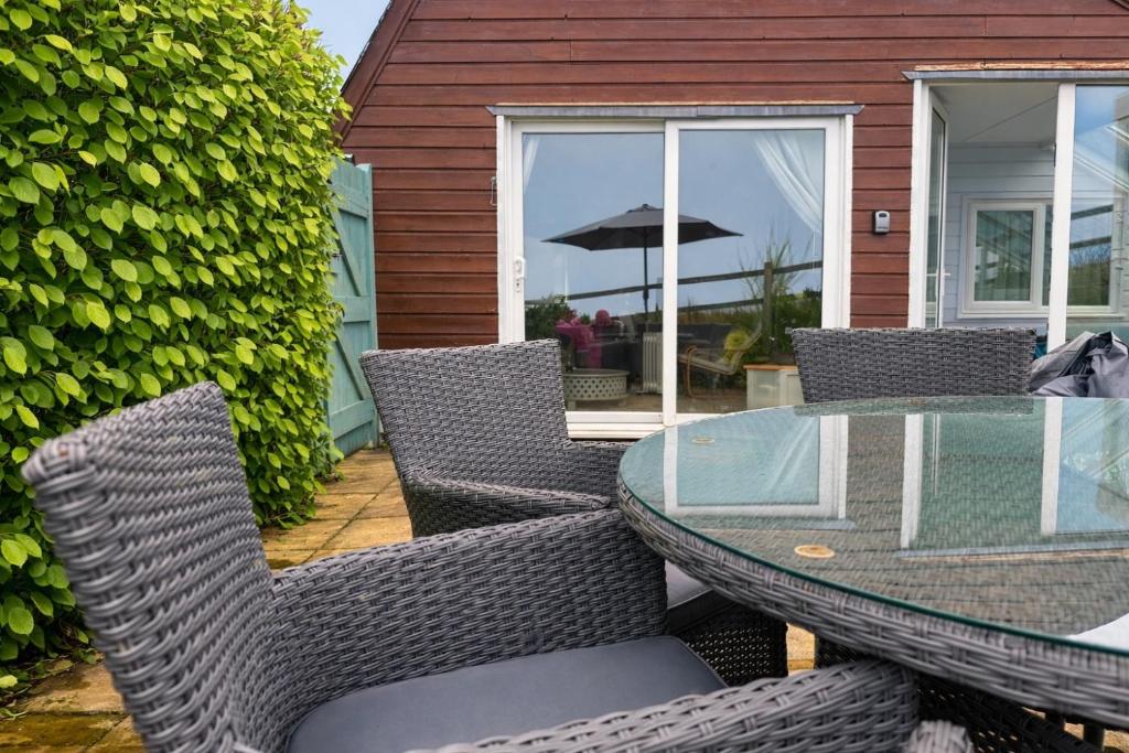 a patio with a glass table and chairs at Coombe Corner Cornwall in Bude