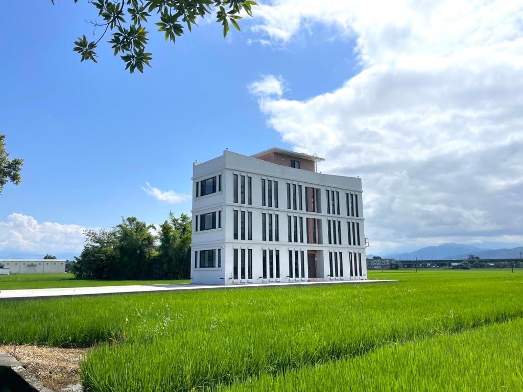 a white building in a field of green grass at Yutian B&B in Zhuangwei