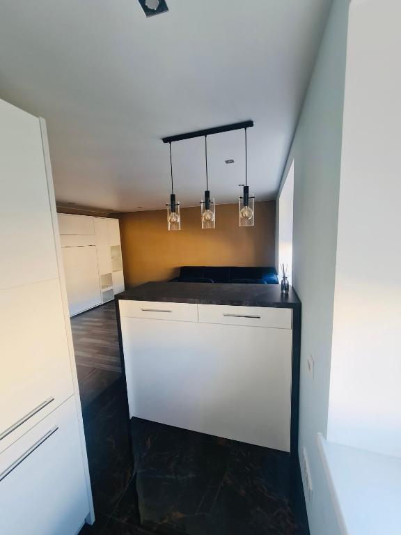 a kitchen with white cabinets and a black floor at G Apartments in Rēzekne