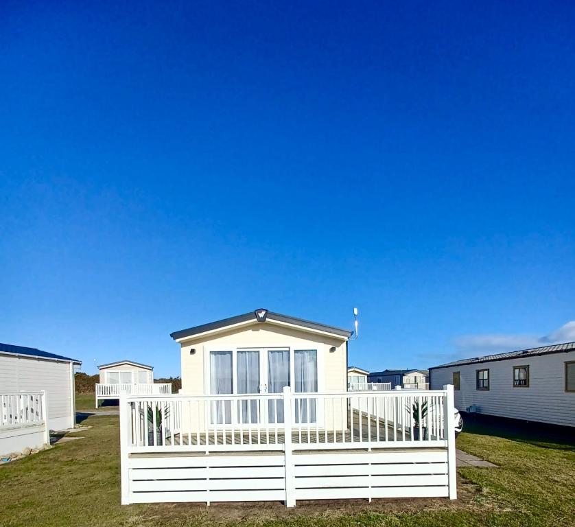 a white house with a white fence in a yard at B17 SilverSands Escape in Lossiemouth