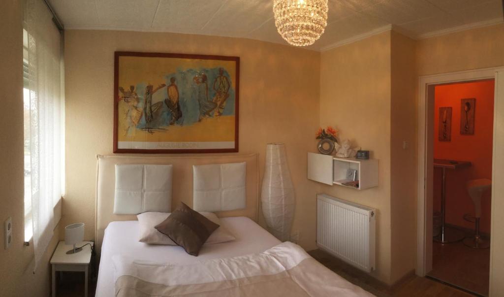 ein Schlafzimmer mit einem weißen Bett und einem Gemälde an der Wand in der Unterkunft Ferienwohnung Grimmer in Weil am Rhein