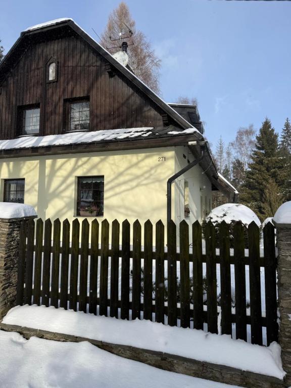a fence in front of a house with snow at Apartmány U Sýkorky in Malá Morávka