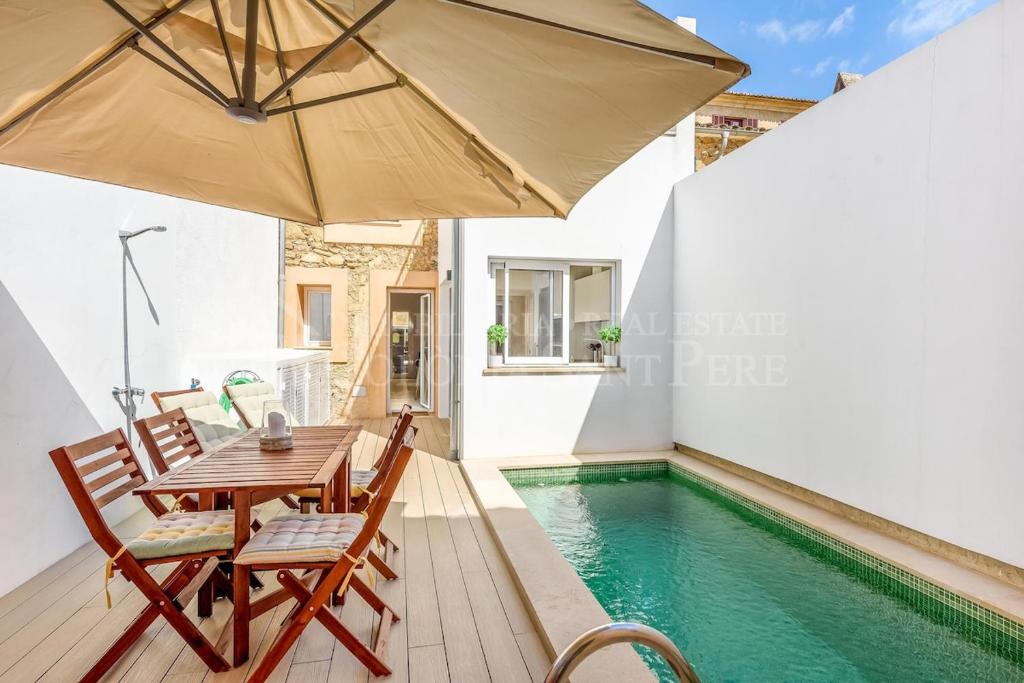 a table and chairs with an umbrella next to a swimming pool at CAN REGALAT - Casa amb piscina a Artà in Artá