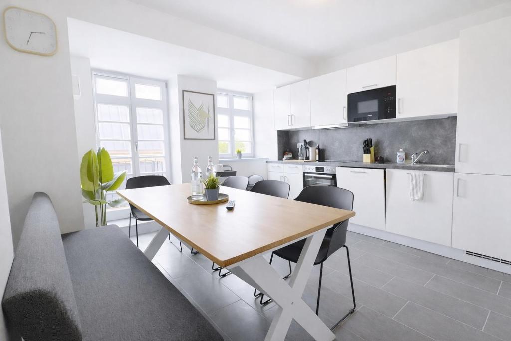 a kitchen and dining room with a wooden table and chairs at Larooms Merseburg - Apartment CS01 - 3 Zimmer, 7 Betten, 2 Bäder, 2 Parkplätze, Balkon & Aufzug in Merseburg