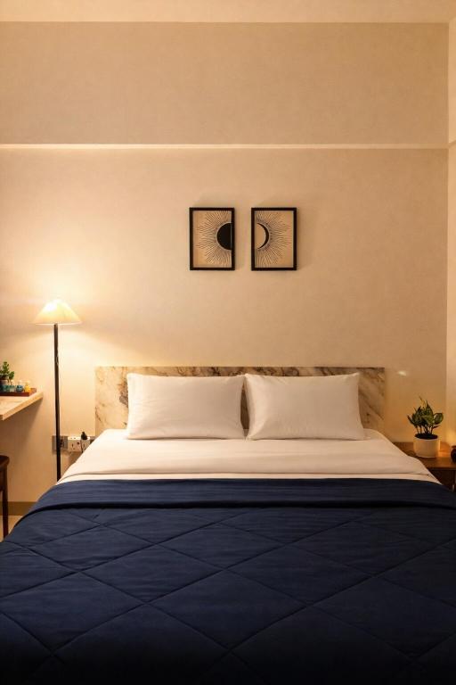 a bed in a room with three pictures on the wall at Elegant 1 RK Studio Balewadi in Pune