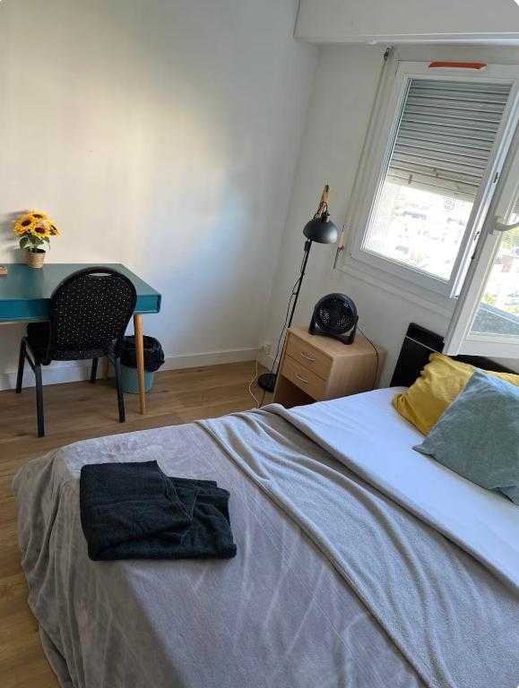 a bedroom with a bed with a desk and a table at Chambre avec vue panoramique in Cachan