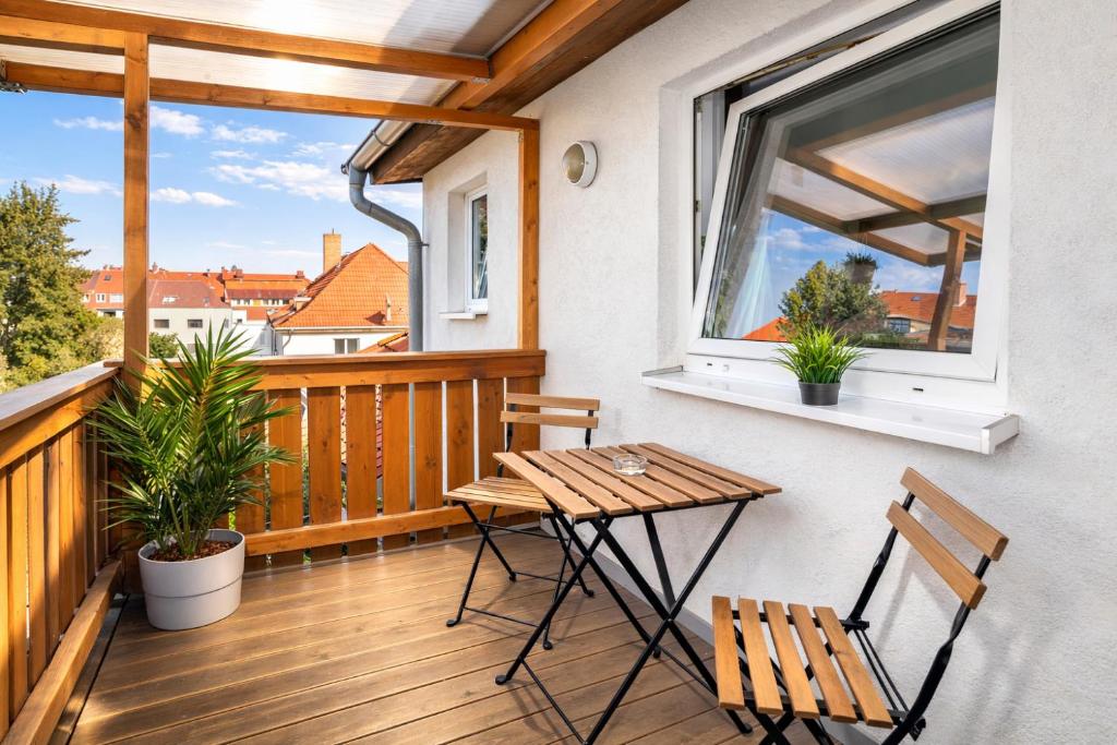 a wooden balcony with a table and chairs on it at Larooms Merseburg - Apartment LP01 - 2 Zimmer, 2 Einzelbetten, 1 Doppelbett, große Couch, Küche, Balkon, Waschmaschine in Merseburg