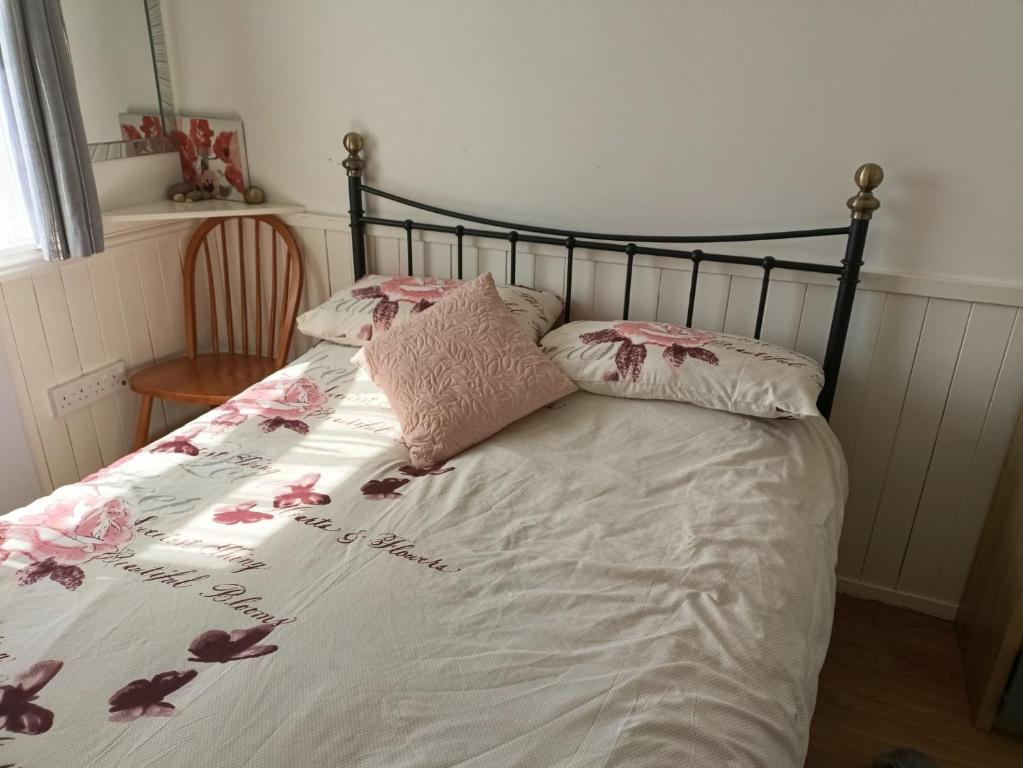 a bedroom with a bed with pink flowers on it at 477 California Sands Chalets in Scratby