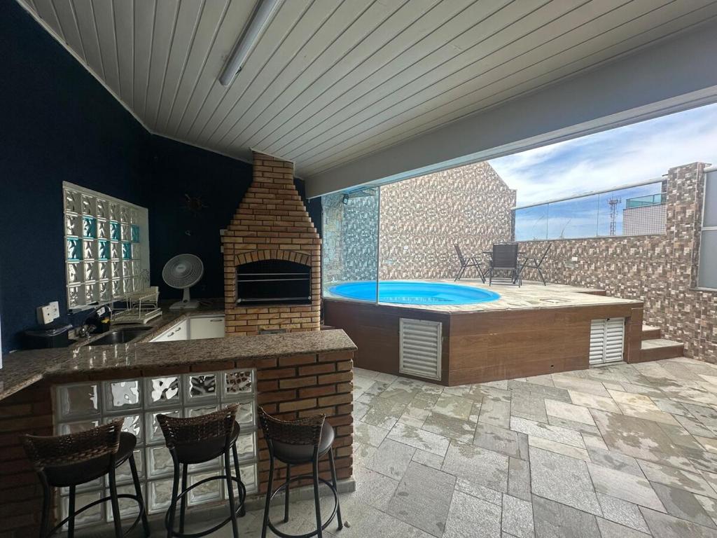 a patio with a hot tub and a bar with chairs at Cobertura Premium com Piscina Exclusiva in Guarujá