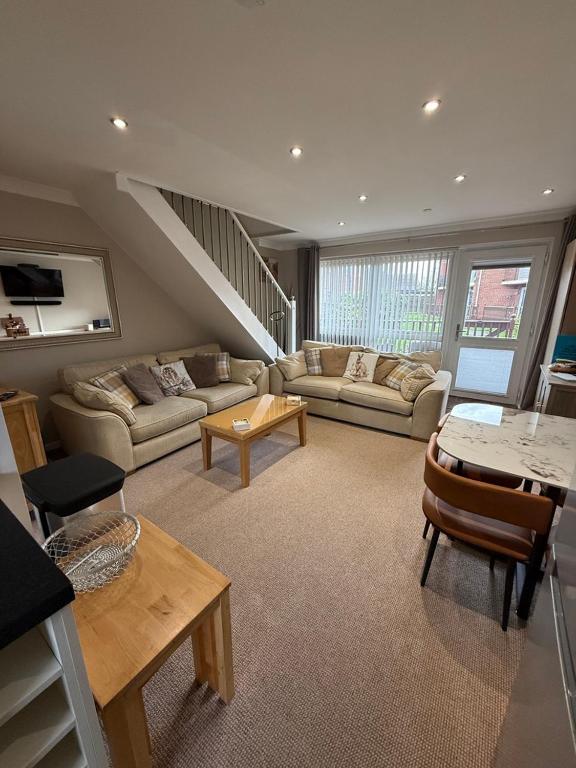 a large living room with couches and a staircase at 30 Waterside in Corton