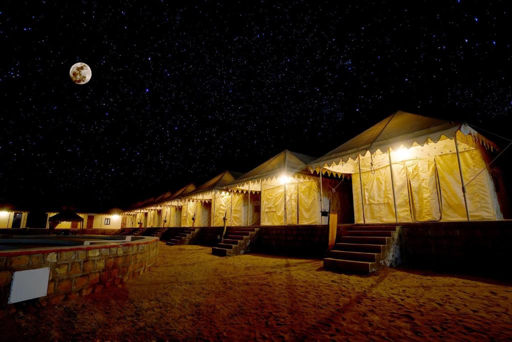 a row of tents in the sand at night at Best desert camp in jaisalmer The Velvet Dunes in Sām