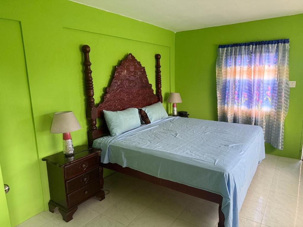 a bedroom with a large bed with green walls at Reggae Moon Guesthouse in Falmouth