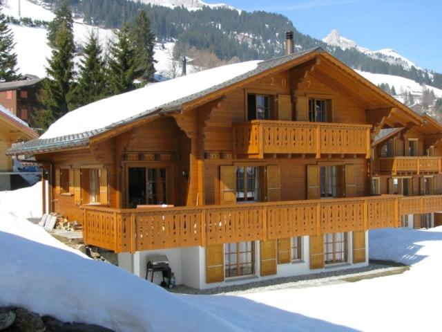 a large wooden house with a snow covered roof at Chalet Le Murier in Leysin